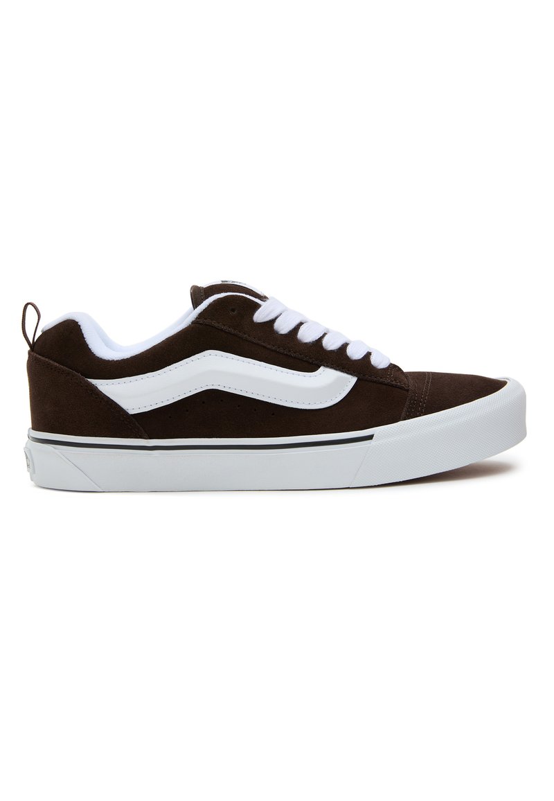 Baskets en daim marron avec un swoosh blanc, un système de laçage blanc, une bande noire, et une semelle en caoutchouc texturé. Étiquette de tirage à l'arrière incluse.