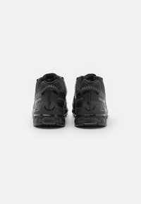 Black running shoes featuring a mesh upper, cushioned sole, and textured detailing on the heel. Reflective accents near the back.