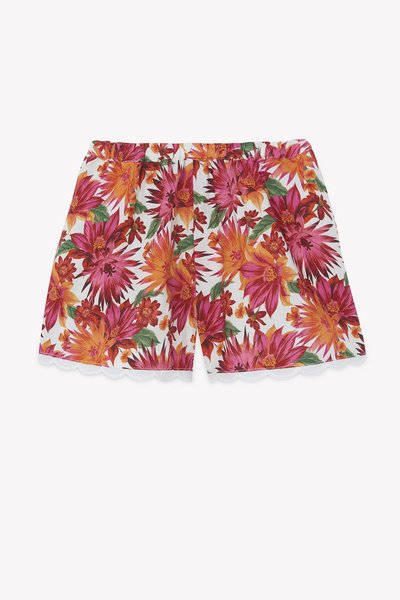 Φλοράλ σορτς με λευκό φόντο και ζωηρά ροζ και πορτοκαλί λουλούδια. Η μέση έχει ελαστική ζώνη και λεπτομέρεια με κυματιστό τελείωμα.