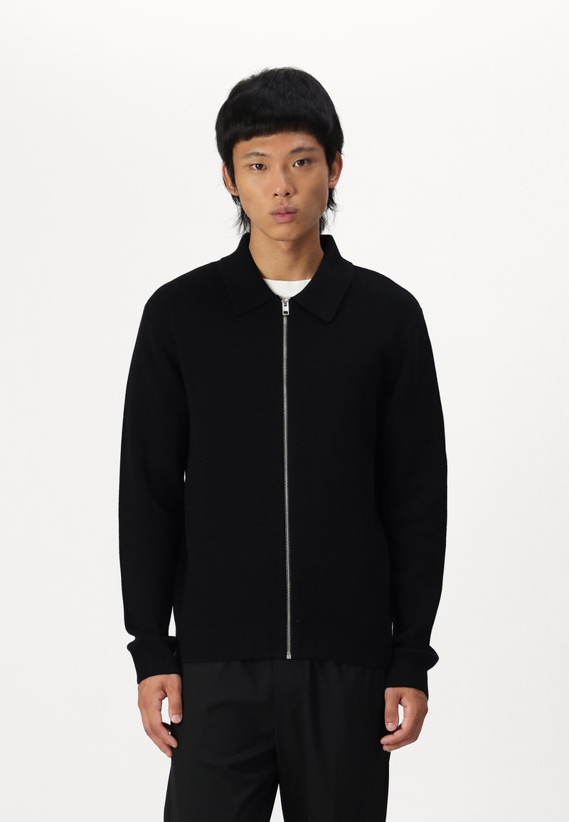 Svart zip-up genser med krage, lange ermer, ribbestrikkede mansjetter og rett fald. Laget av et mykt, teksturert stoff, egnet for lagdeling.