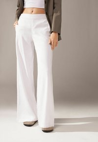 Vita vida byxor med breda ben tillverkade av ett lätt tyg, med en slät yta, hög midja och minimala sömnadsdetaljer.