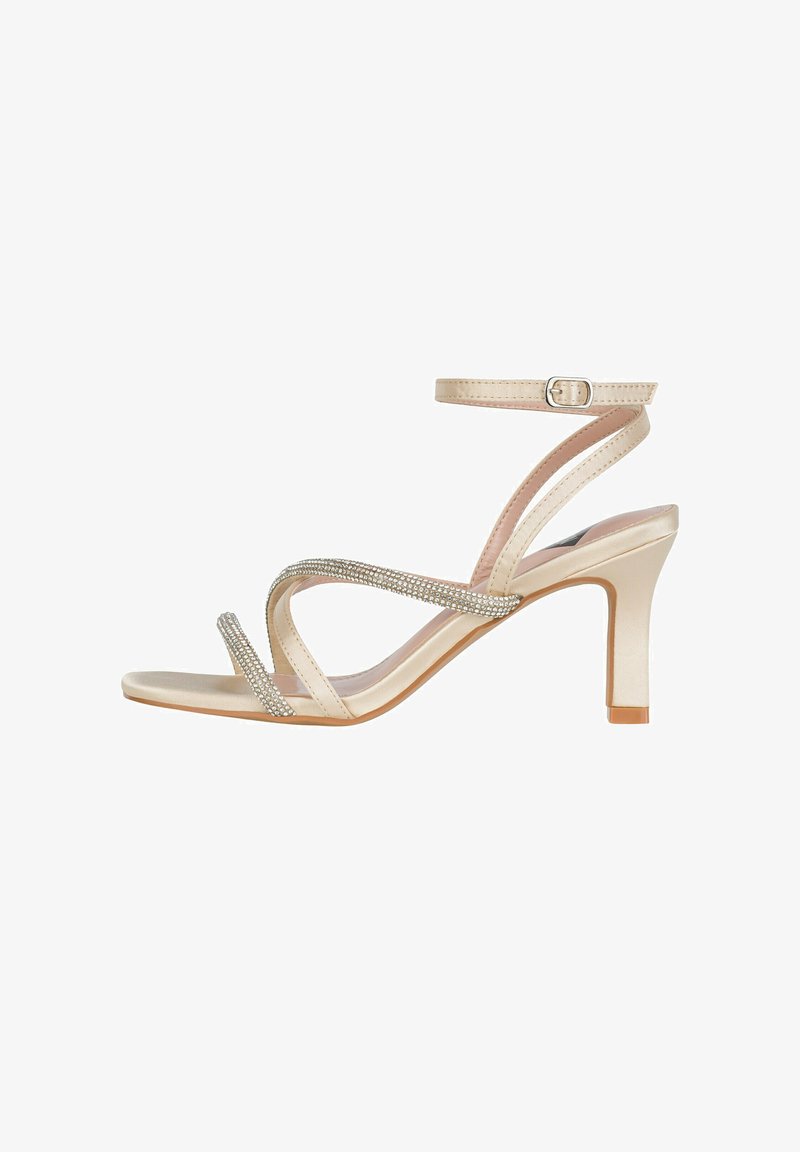 Beige satijnen sandaaltjes met hoge hakken, voorzien van kruislings geplaatste banden versierd met rhinestones, een verstelbare enkelband en een taps toelopende hak.
