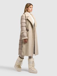 Beige dynejakke med blød tekstur, dobbeltradet design, stor krave og sidelommer, kombineret med cremefarvede snestøvler.