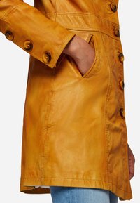 Yellow leather coat with a smooth texture, featuring a fitted design, five buttons, and side pockets, displayed at the sleeve and hem.