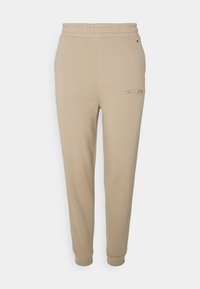 Beige Baumwoll-Jogginghosen mit elastischem Bund, Bündchen an den Knöcheln und einem kleinen gestickten Logo auf der linken Seite. Weicher Stoff, gerade Passform.