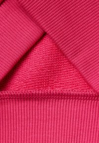 Tejido de punto fucsia que muestra una textura acanalada con acentos suaves. El material presenta una mezcla de texturas finas y gruesas.