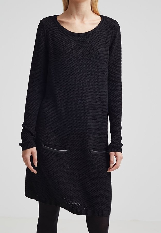 Robe noire en maille avec manches longues, encolure ronde, et deux poches avant, présentant un motif texturé et une coupe décontractée.