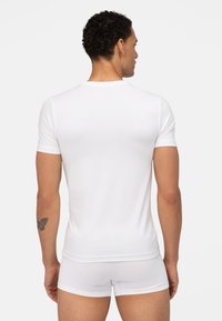 Weißes, tailliertes T-Shirt aus glattem Baumwollstoff, mit kurzen Ärmeln und Rundhalsausschnitt, von hinten betrachtet. Das Material wirkt leicht dehnbar.
