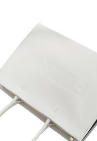 Sac fourre-tout en cuir blanc avec logo en relief, de forme plate, double poignées et accents en métal doré. Fini texturé, design minimaliste.