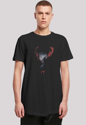 Black t-shirt featuring a graphic of a clown character with red hair and white face paint, holding a finger to its lips, with "IT" in red below.