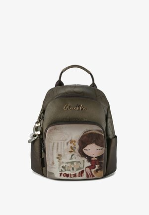 Sac à dos en similicuir vert et marron avec une illustration d'une fille sur la poche avant, doté d'accents dorés et d'un charm décoratif.
