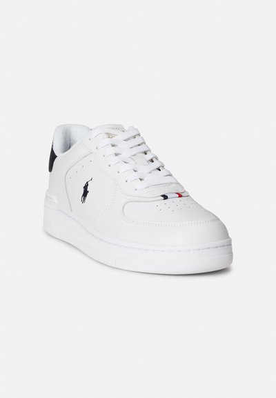 Biały skórzany sneaker o zaokrąglonym nosku, perforowanym wzorze i białej gumowej podeszwie. Posiada czarny akcent na pięcie oraz logo po boku.