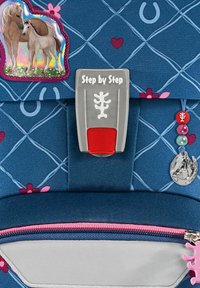 Blue backpack featuring a diamond pattern, horse graphics, gray buckle labeled "Step by Step," pink zipper, and decorative charms.