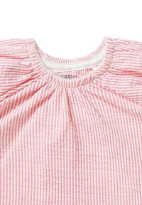 Czerwono-biała, w paski bluzka z marszczonym dekoltem, krótkimi rękawami i miękką teksturą. Nazwa marki widoczna przy kołnierzyku.