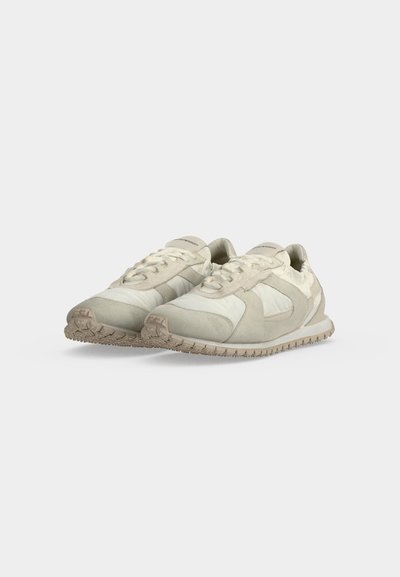 Ζευγάρι ανοιχτόχρωμα casual sneakers με δέσιμο στο μπροστινό μέρος και υφασμένα μπεζ πέλματα σε απλό ανοιχτογκρι φόντο.