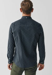Marineblauwe langemouwen shirt met een subtiel wit x-patroon, met knoopsluiting kraag en manchetten, gemaakt van gestructureerde stof.