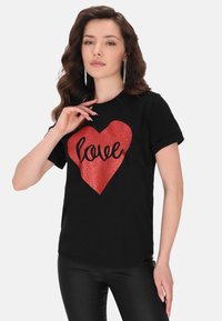 Sort t-shirt med et stort rødt glitrende hjertegrafik og ordet "kærlighed". Korte ærmer og en afslappet pasform.