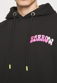 Sweat à capuche noir avec texte "BARROW" rose vif sur la poitrine, avec cordons noirs à embouts jaune néon et œillets métalliques.