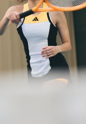 Sporting dress with a white body, black side panels, and a yellow trim. Features a high neckline and an Adidas logo on the chest.