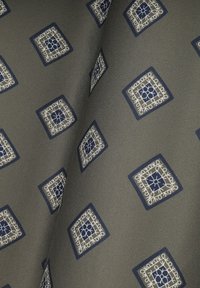 Materiał w wzór z geometrycznym designem w kolorze granatowym i białym na szarym tle, z teksturowanym wykończeniem i misternymi detalami.