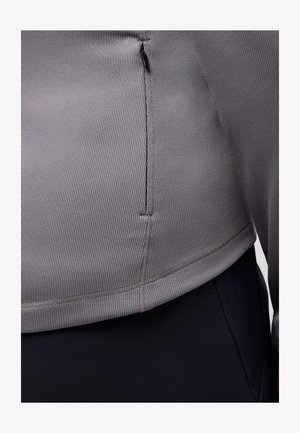 Grauer gerippter Stoffoberteil mit einem seitlichen Reißverschlussdetail, über einem dunklen Taillenbund, der ein figurbetontes und modernes Design betont.