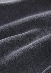 Tejido de textura gris oscura con una superficie suave y aterciopelada, que muestra sutiles ondulaciones y un patrón uniforme en toda su extensión.