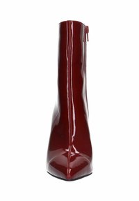 Bottine en cuir verni rouge avec un bout pointu, un design épuré et une fermeture à zip à l'arrière. Texture lisse et finition ultra brillante.