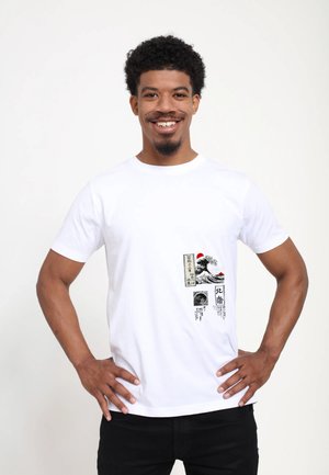 Bílý bavlněný tričko s grafickým potiskem vln a japonským textem v černé a červené barvě, s krátkými rukávy a kulatým výstřihem.