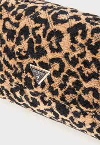 Leopardprint taske med en quiltet tekstur, prydet med et guldfarvet trekantet logo. Farverne inkluderer en tan baggrund og sorte mønstre.