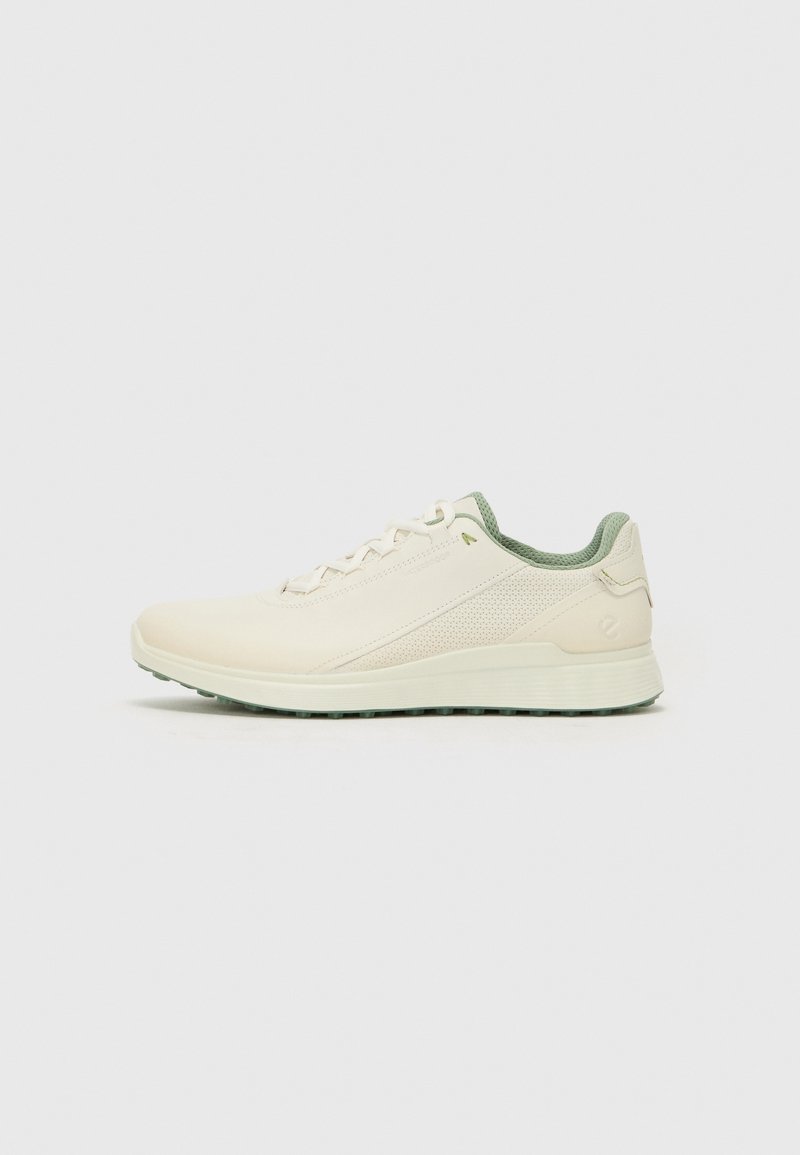 Light beige sneaker with green accents, featuring a textured upper, lace-up design, and a chunky white sole with a patterned tread.