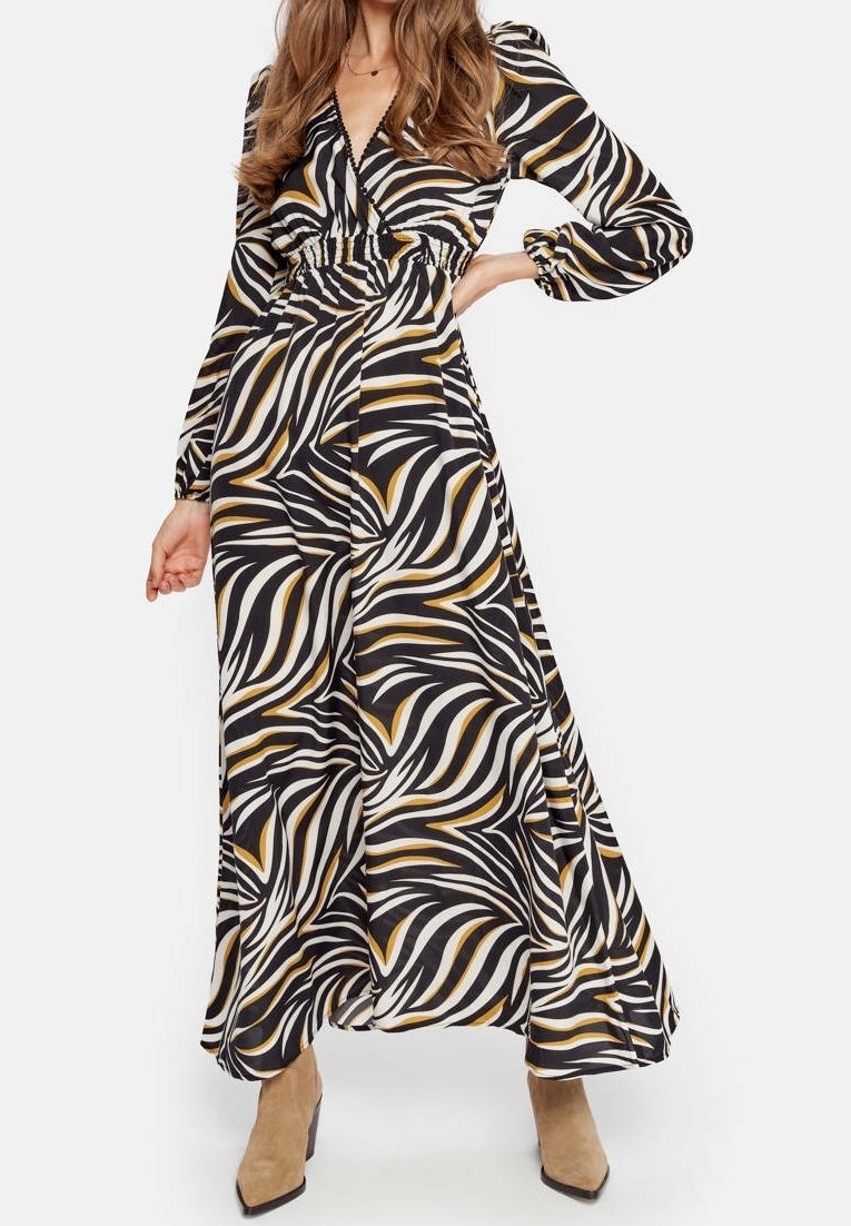 Robe à manches longues noir et blanc avec des motifs tourbillonnants audacieux en jaune et or ; dotée d'un col en V et d'une taille cintrée pour une silhouette ajustée.