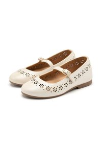 Chaussures Mary Jane en cuir crème avec des motifs floraux perforés, des bouts ronds et des boucles réglables, dotées d'une semelle brune basse.