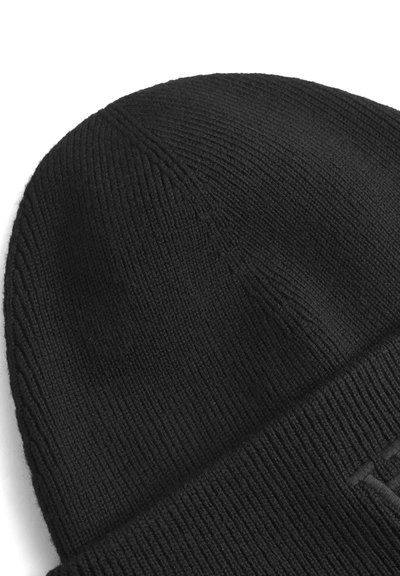 Bonnet en tricot noir avec une texture côtelée, doté d'un revers plié. Le matériau semble doux et extensible, adapté pour être porté par temps froid.