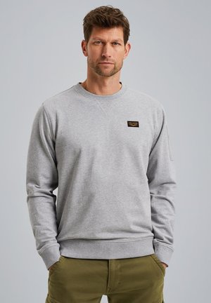 Grijze sweatshirt met een ronde hals en lange mouwen. Beschikt over een klein zwart logo op de borst en ribbelmanchetten en -zoom.