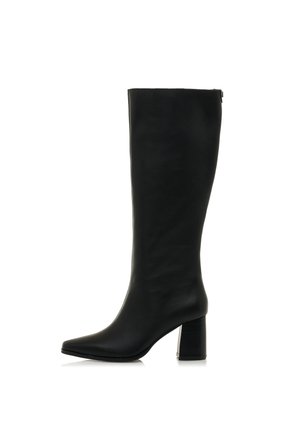 Bota de cuero negra hasta la rodilla con un tacón cuadrado y punta afilada, mostrada de lado sobre un fondo blanco.