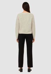 Maglione grigio chiaro in maglia texturizzata con vestibilità ampia, abbinato a pantaloni neri a gamba dritta e scarpe nere.