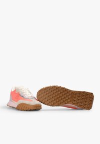 Zapatilla de running con parte superior de material mixto en beige, rosa y gris, con una suela de goma texturada y protuberancias redondas para mayor tracción.