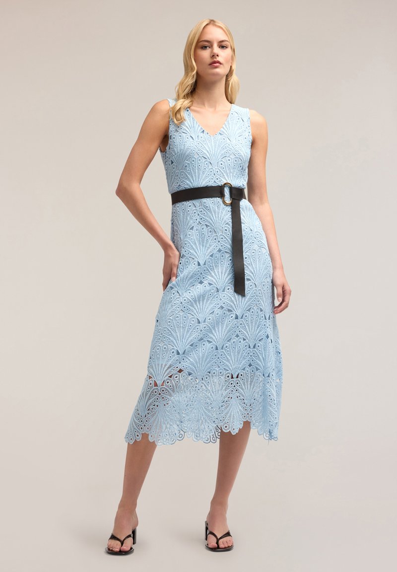 Rochie din dantelă bleu deschis, cu decolteu în V, fără mâneci și curea neagră cu cataramă circulară. Materialul este decorat cu modele tăiate complicate.