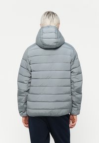 Lys grå pufferjakke med hætte, der har vandrette syninger og en glat, blank overflade. Designet inkluderer en afslappet pasform.
