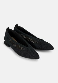 Zapatos planos de punto negros con forma de punta almendrada, superficie texturizada y un pequeño tacón cuadrado; presentan patrones recortados en los lados.