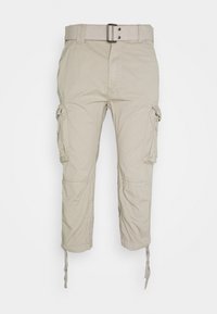 Pantalons cargo beiges avec une ceinture, dotés de poches latérales, de poignets ajustables et d'une texture de tissu légère.