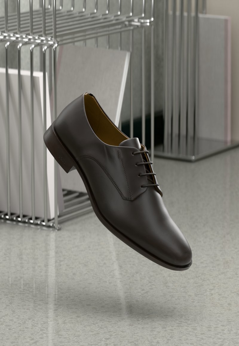 Scarpa in pelle marrone con finitura liscia, caratterizzata da un punta arrotondata, design con lacci e dettagli di cucitura sottile. Posizionata su uno sfondo neutro.