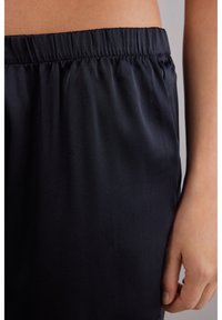 Zwarte satijnen shorts met een bijeen geraapte elastische tailleband en een soepele textuur, met handplaatsing aan de zijkant.