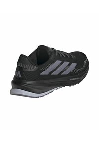 Black athletic shoe with a textured mesh upper, three gray stripes, and a cushioned sole. Features a secured lace-up design and durable heel.