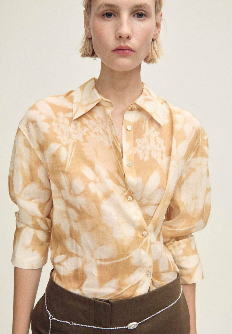 Camicia di lino a fiori in morbidi toni pesca e crema, con colletto, chiusura a bottoni e maniche arrotolate.