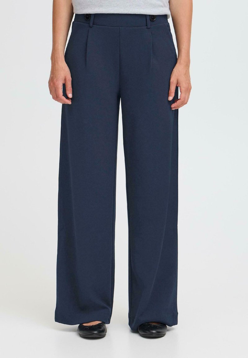 Navy wide-leg trousers made of smooth fabric, featuring front pleats, a flat waistband with two buttons, and a relaxed fit.