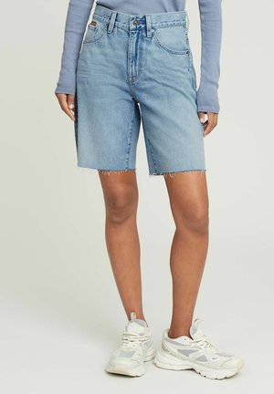 Lichtblauwe denim shorts met een hoge taille en rafelige zoom. Gekocht met witte sneakers met gaas- en solide accenten.