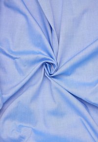 Tessuto blu chiaro con una consistenza liscia, leggermente stropicciato, che presenta una consistenza uniforme e una morbida caduta. Adatto a varie applicazioni tessili.