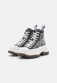Sneaker alte con stampa grafica nera, lacci bianchi e suola bianca spessa. Presentano linguette ad anello per indossarle facilmente.