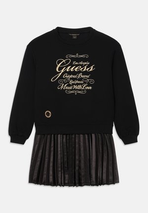 Schwarzes Sweatshirtkleid mit plissiertem Rock, mit goldbesticktem Text und einem dekorativen Ring am Saum. Weicher Stoff, lässige Passform.